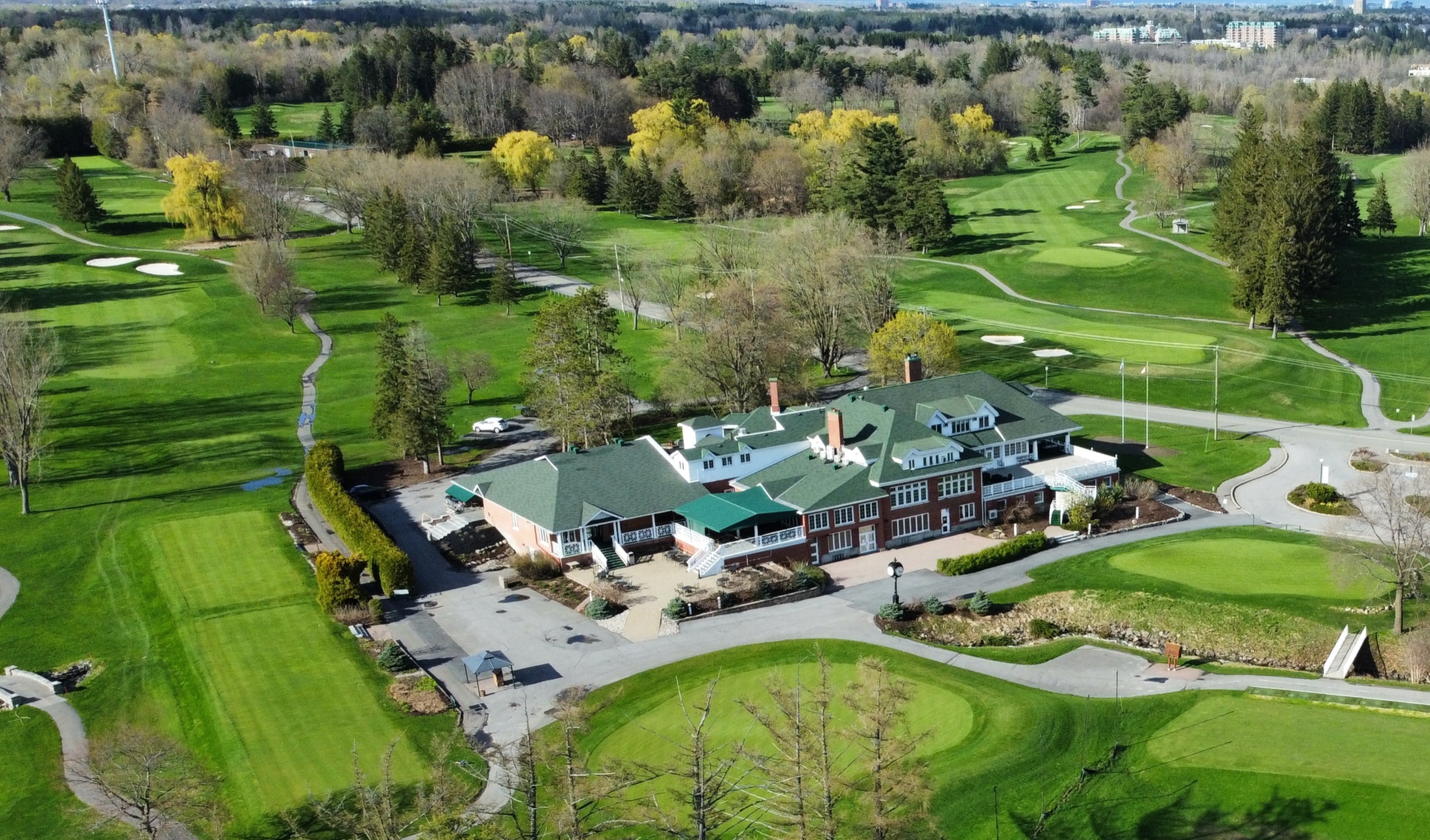 Rivermead's red-brick, green-roofed clubhouse seen from above, fairways on every side