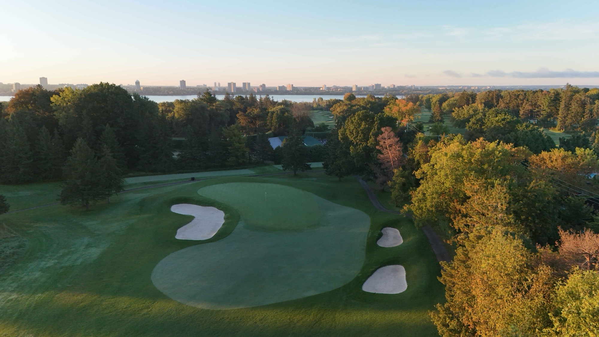 A green complex at dawn with the Ottawa River and city skyline on the horizon