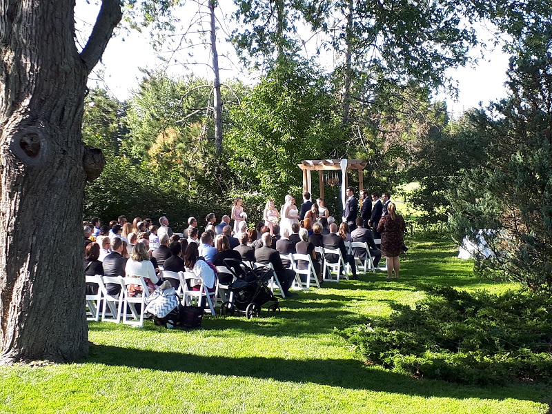 An outdoor wedding ceremony under mature trees on the club grounds